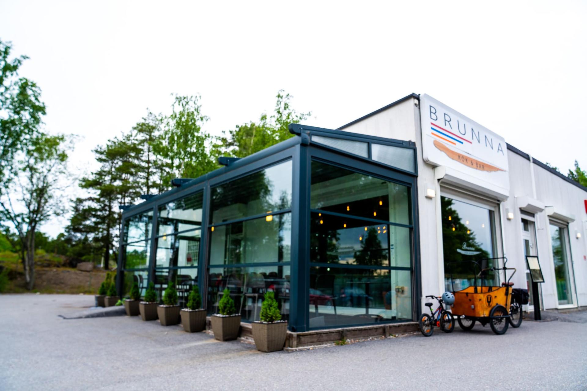 Fasaden på BRUNNA KÖK & BAR med uteservering och entré